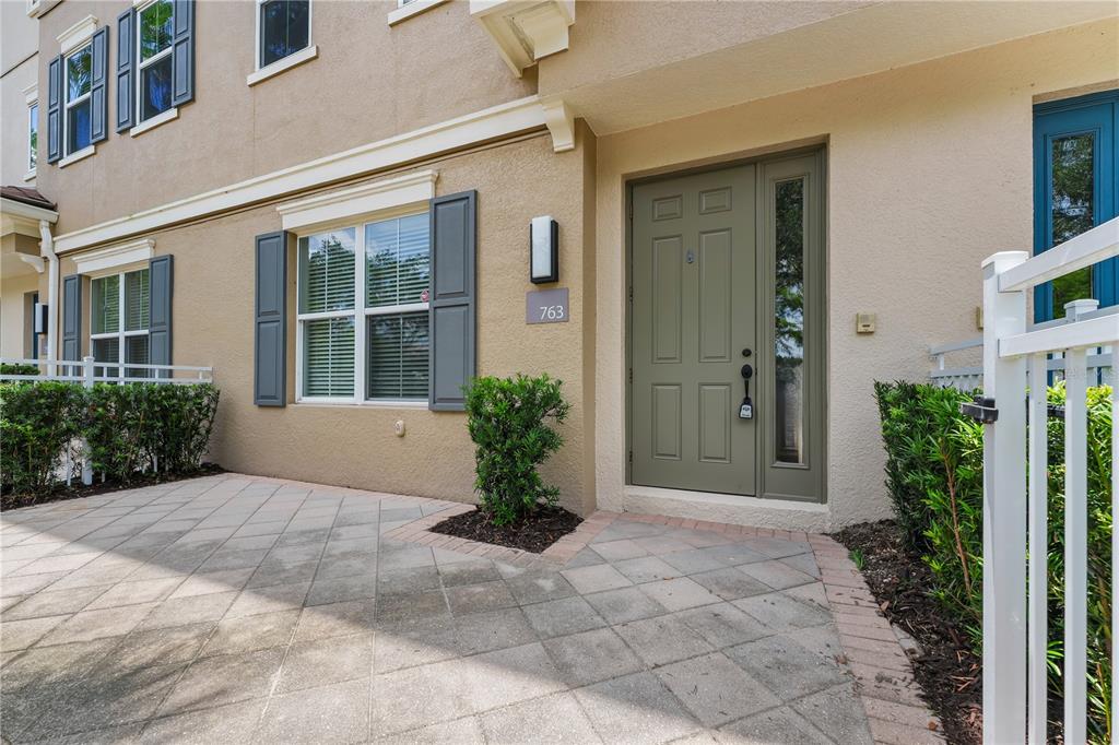 The exterior of a tan townhouse features a green front door and a paved patio — 763 GREYBULL RUN, LAKE MARY, FL