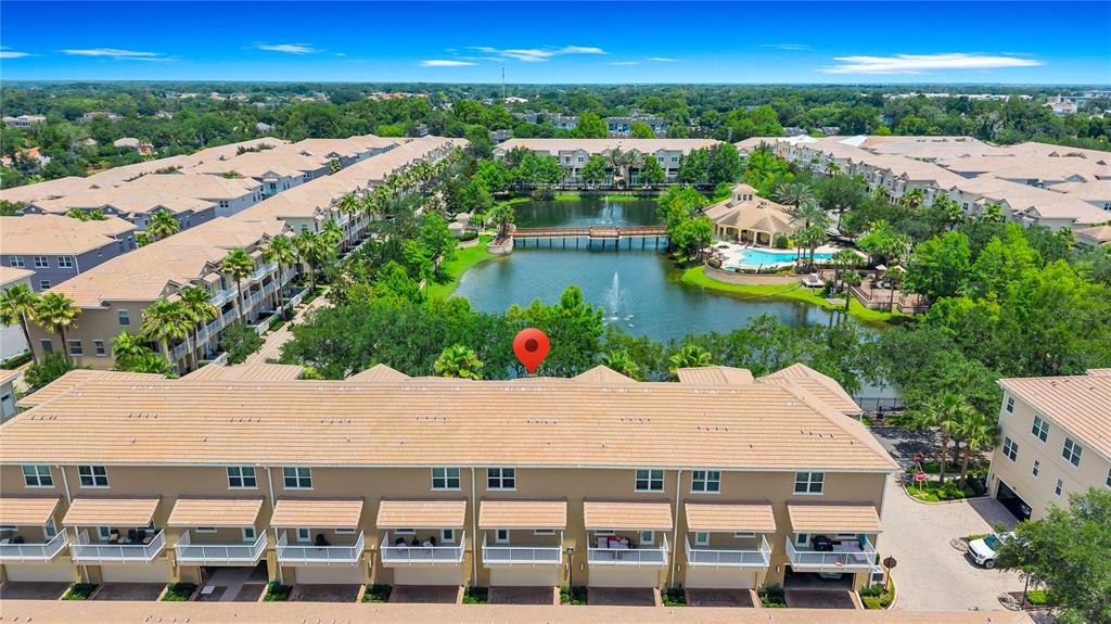 An aerial view shows a multi-story townhouse complex with a central pond and pool — 763 GREYBULL RUN, LAKE MARY, FL