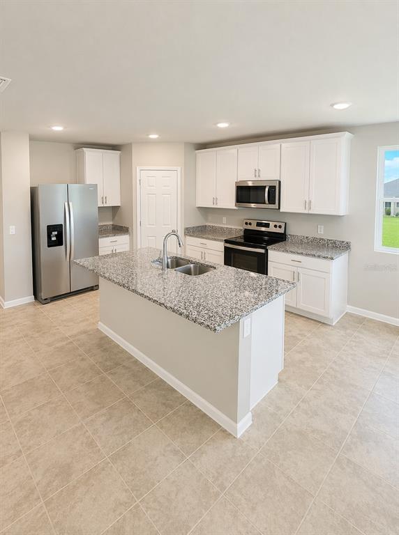 A kitchen features white cabinets, granite countertops, a center island, and stainless steel appliances — 1505 CONGAREE STREET, DAVENPORT, FL