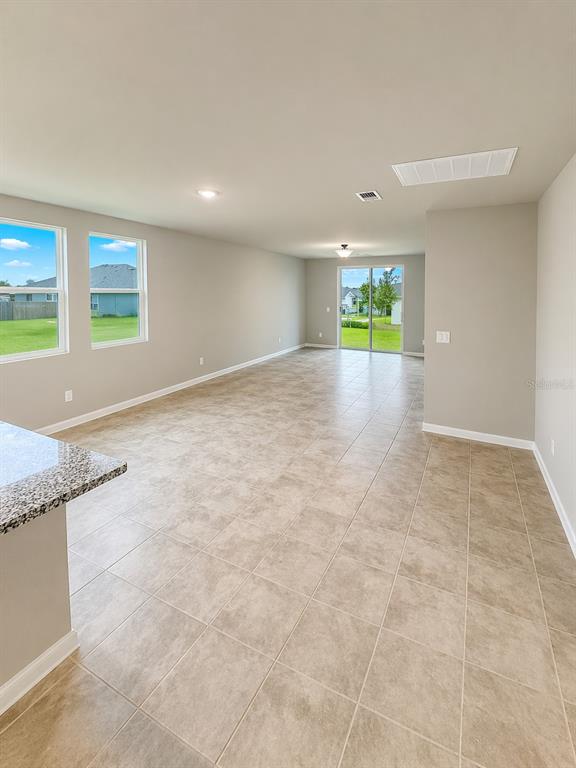 An open-concept living area features light-colored tile flooring, neutral walls, and sliding glass doors — 1505 CONGAREE STREET, DAVENPORT, FL