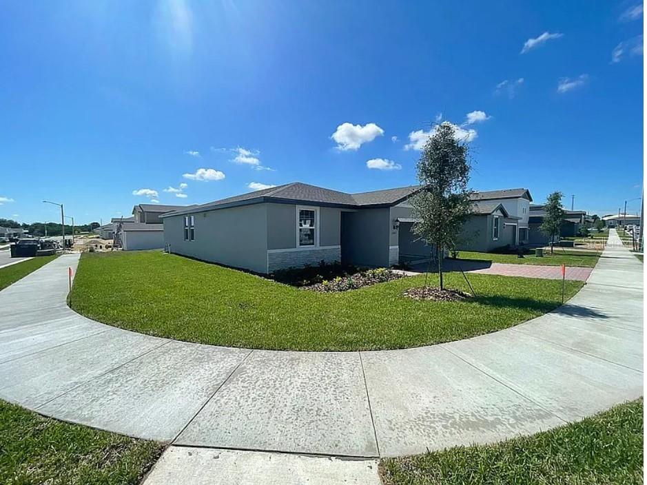 A corner lot view of a single-story gray house with a paved driveway and sidewalk — 1505 CONGAREE STREET, DAVENPORT, FL