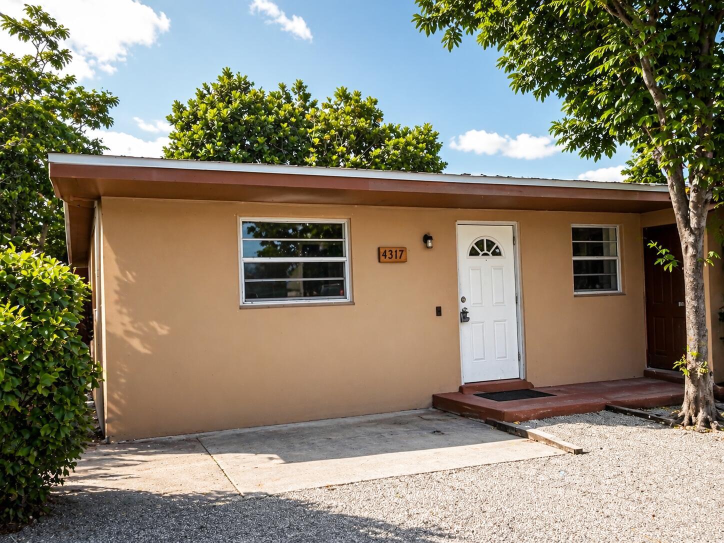 A single-story tan house with a white front door and a concrete driveway — 4317 Cocoanut Road, West Palm Beach FL 33406, WEST PALM BEACH, FL