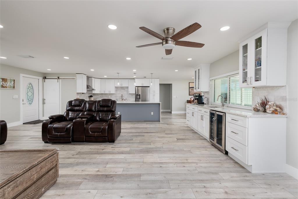 An open-concept kitchen and living area features white cabinetry, a gray island, and wood-look flooring — 9773 1ST STREET NE, ST PETERSBURG, FL