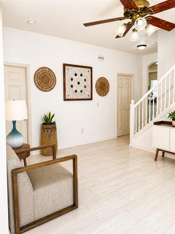 A bright entryway features a staircase, a beige armchair, and decorative wall art — 7942 ENDLESS SUMMER COURT, LAND O LAKES, FL