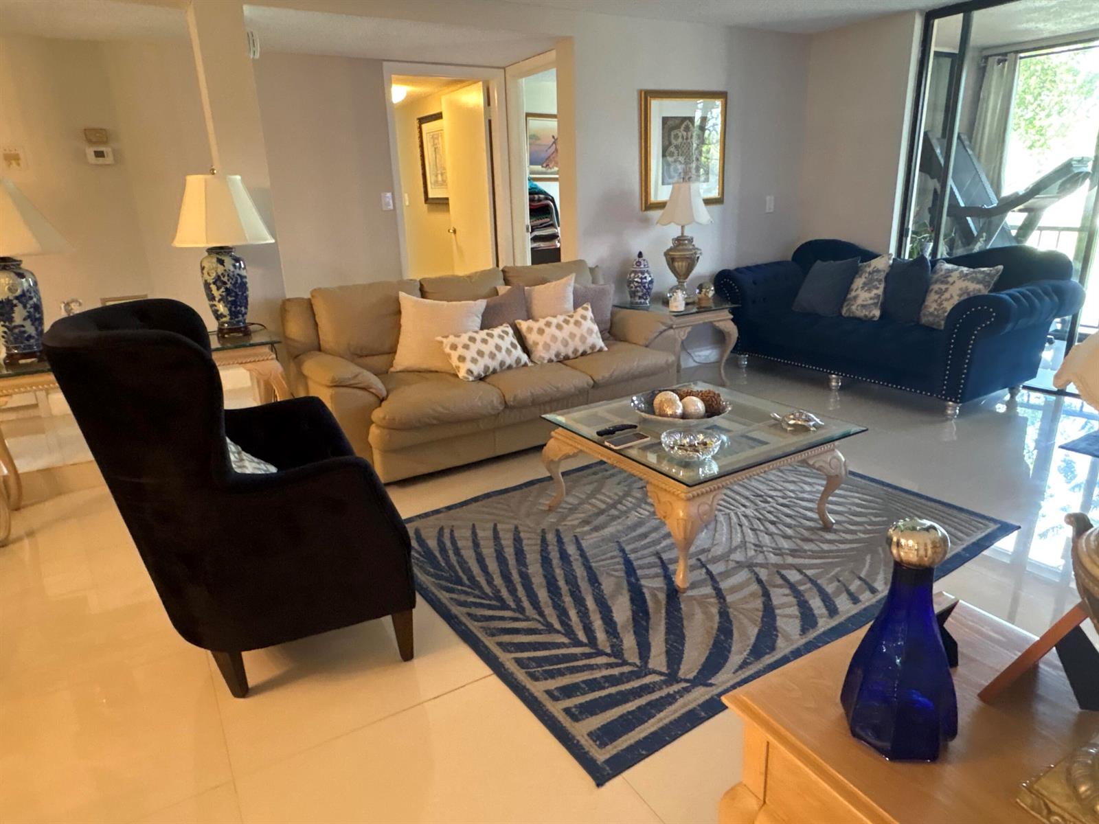 A living room features a beige sofa, a blue velvet sofa, and a patterned area rug — 3730 Inverrary Drive # 2t, Lauderhill FL 33319, LAUDERHILL, FL