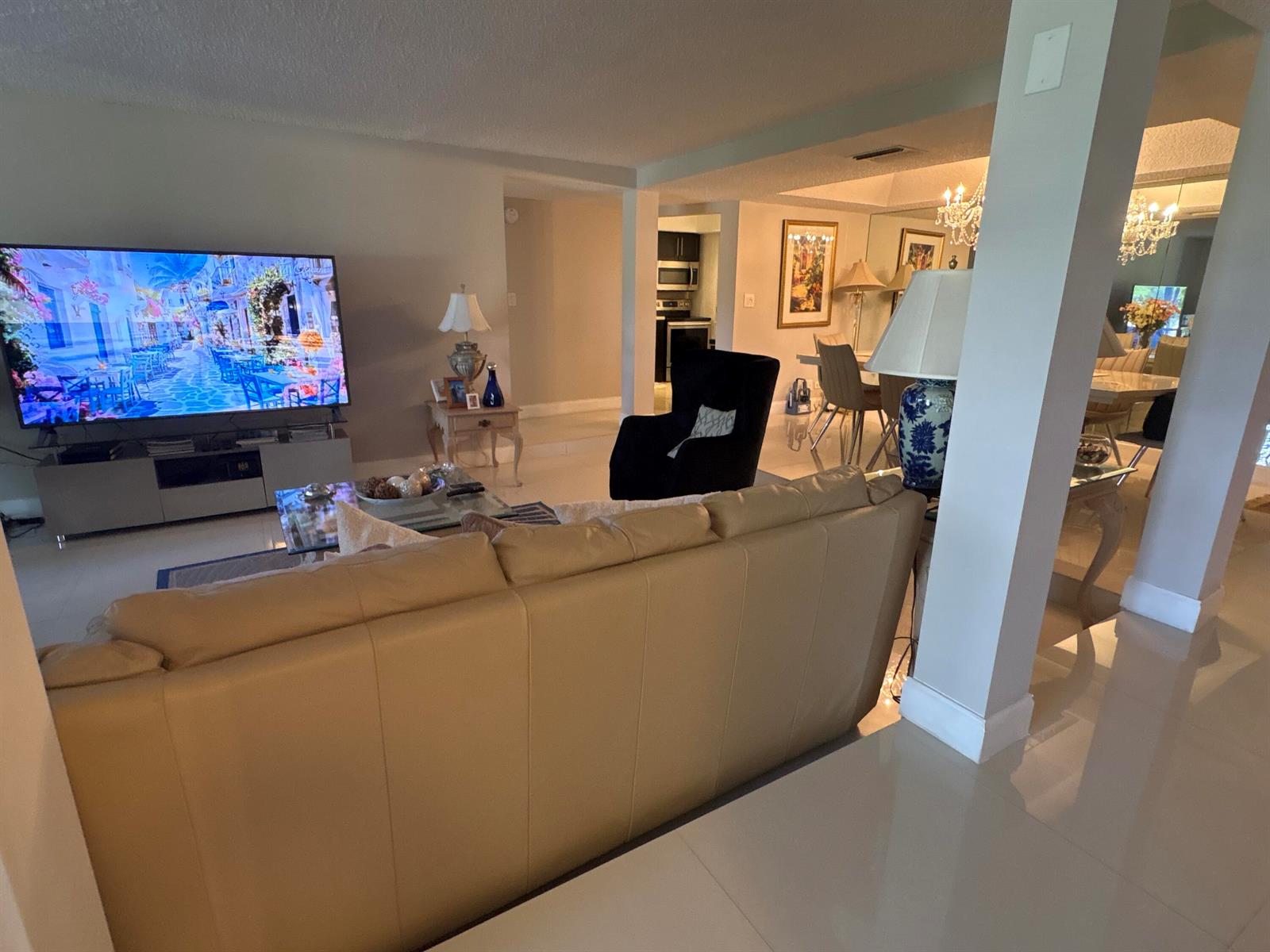 A living room with a beige leather sofa, a large television, and an adjacent dining area — 3730 Inverrary Drive # 2t, Lauderhill FL 33319, LAUDERHILL, FL