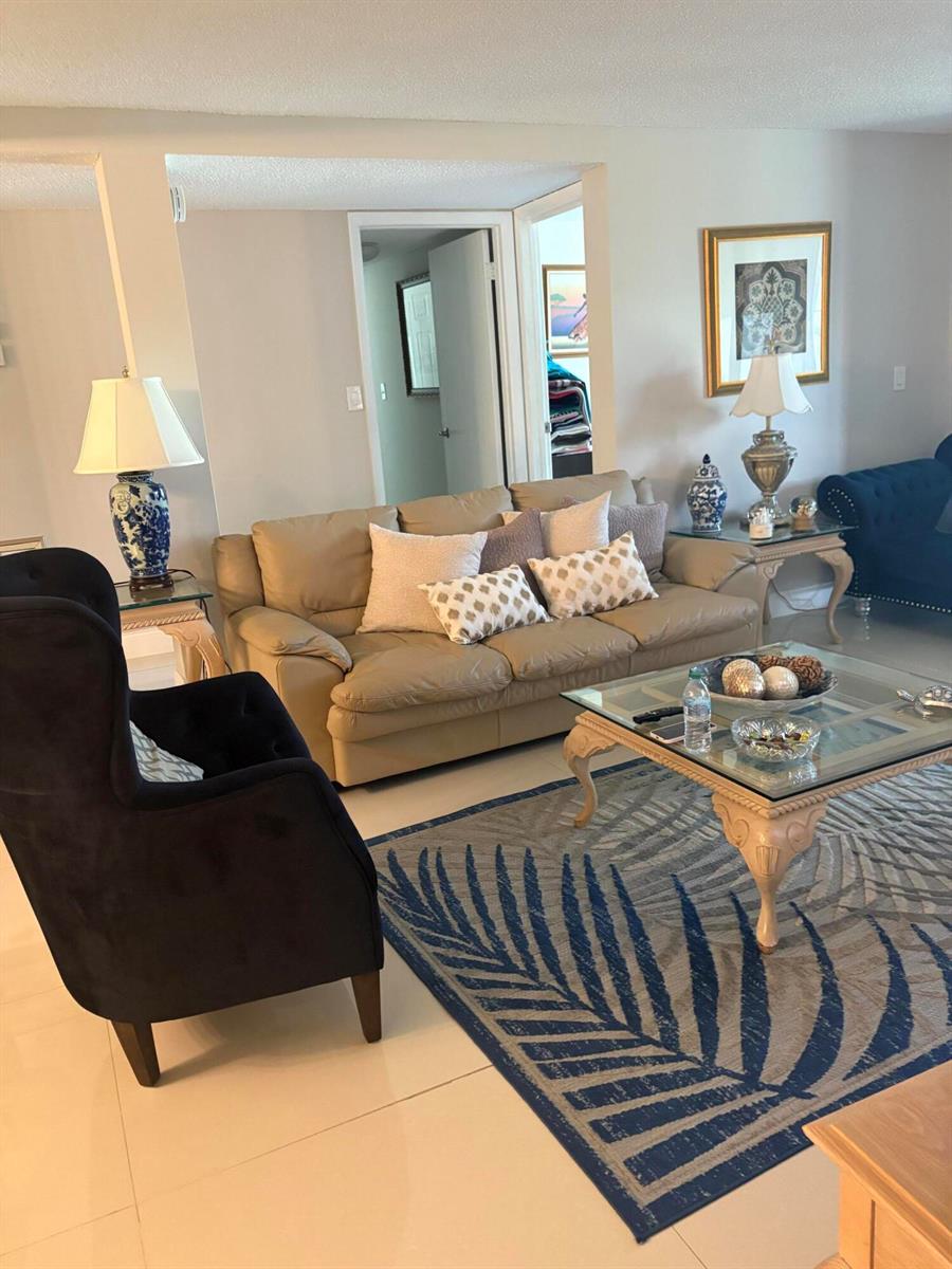 A living room features a beige sofa, a dark armchair, and a patterned area rug — 3730 Inverrary Drive # 2t, Lauderhill FL 33319, LAUDERHILL, FL
