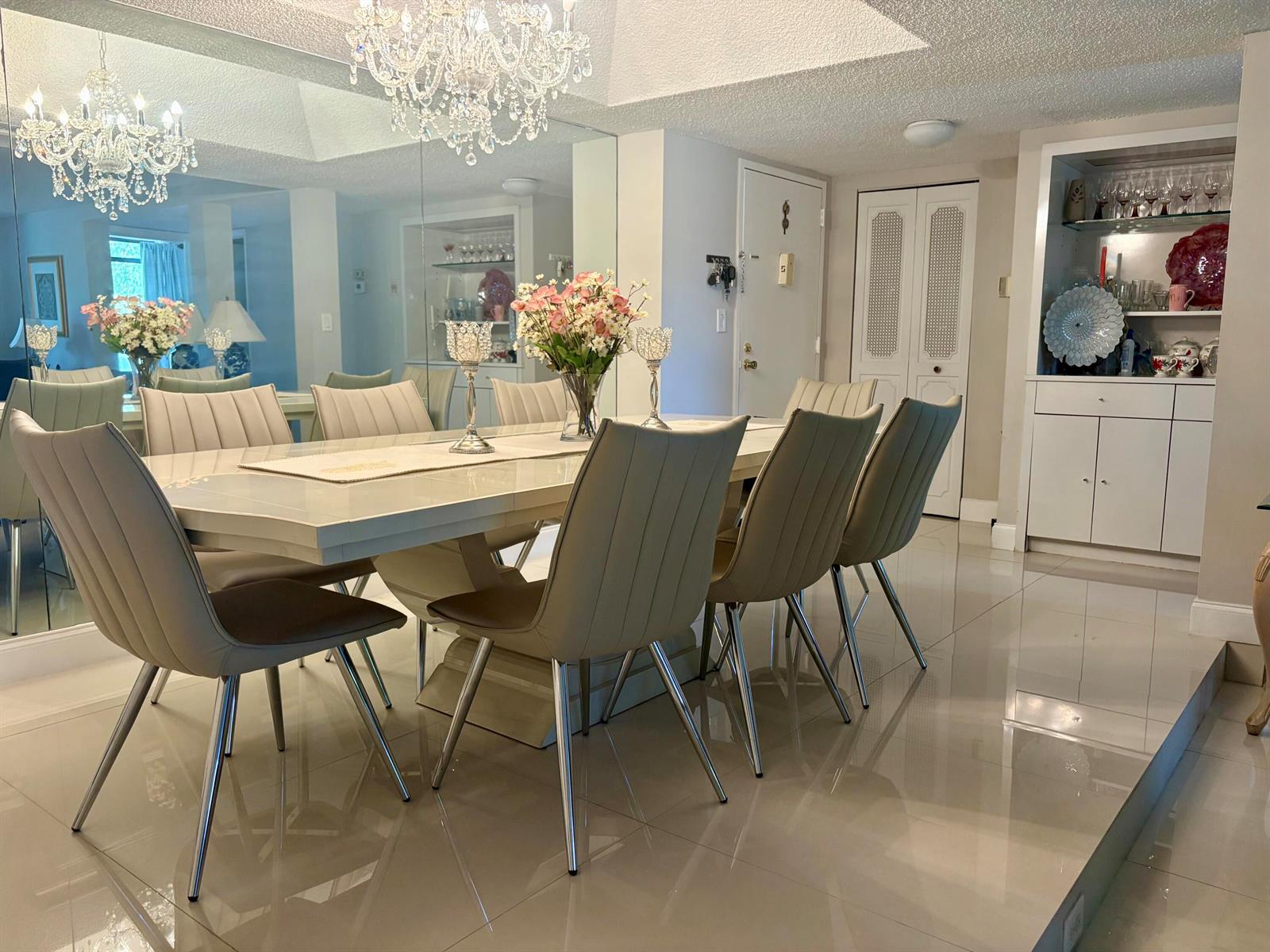 A dining room features a glossy table, six upholstered chairs, a crystal chandelier, and mirrored walls — 3730 Inverrary Drive # 2t, Lauderhill FL 33319, LAUDERHILL, FL