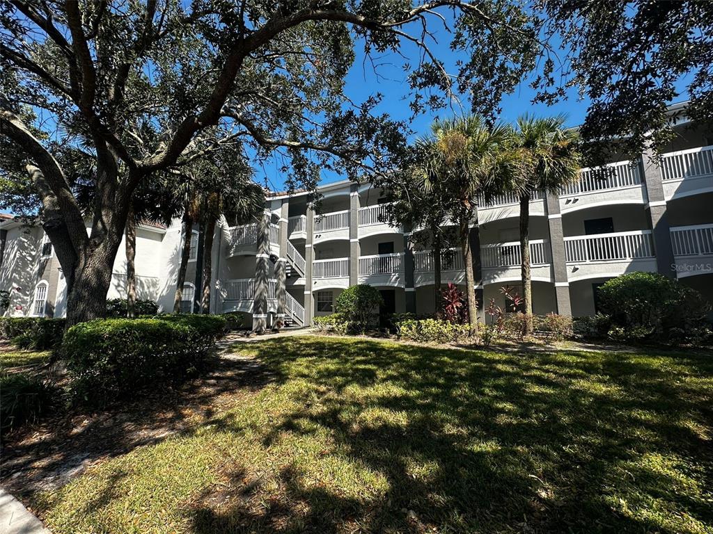 A multi-story apartment building with white balconies and palm trees in a grassy courtyard — 14013 FAIRWAY ISLAND DRIVE UNIT 415, ORLANDO, FL