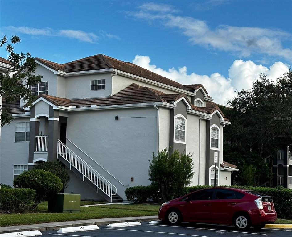 A multi-story apartment building with a white exterior, brown tile roof, and outdoor stairs — 14013 FAIRWAY ISLAND DRIVE UNIT 415, ORLANDO, FL