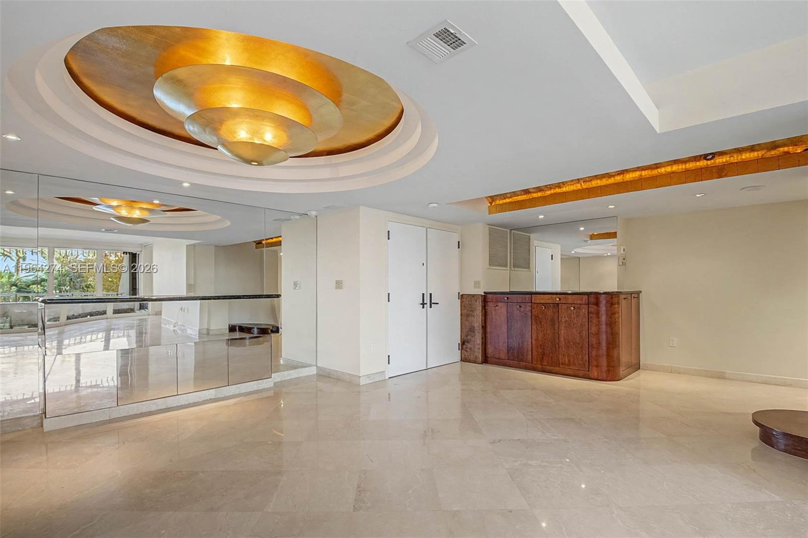 A room with marble floors, a gold tiered ceiling light, and a wooden wet bar — 3 Grove Isle Dr # C208, Miami FL 33133, MIAMI, FL