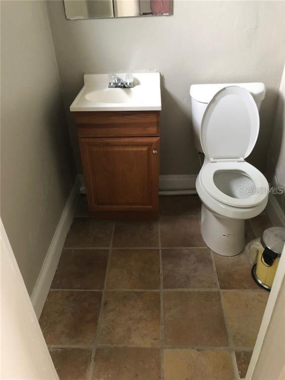 A small bathroom features a wood vanity, a white sink, and a white toilet — 629 N SEMORAN BOULEVARD, ORLANDO, FL