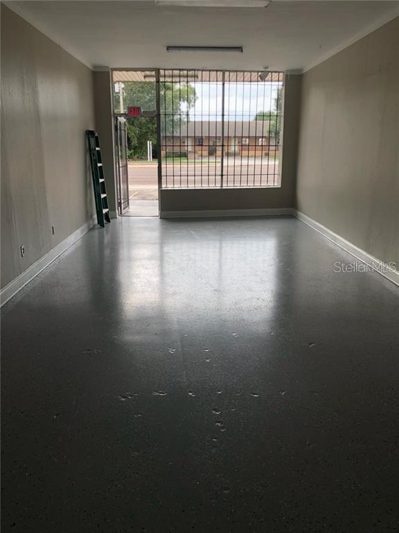 An empty commercial space features gray epoxy flooring, beige walls, and a large windowed entrance — 629 N SEMORAN BOULEVARD, ORLANDO, FL