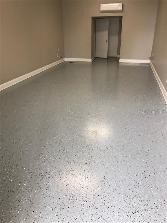 A room with light gray walls, white baseboards, and a speckled epoxy floor finish — 629 N SEMORAN BOULEVARD, ORLANDO, FL