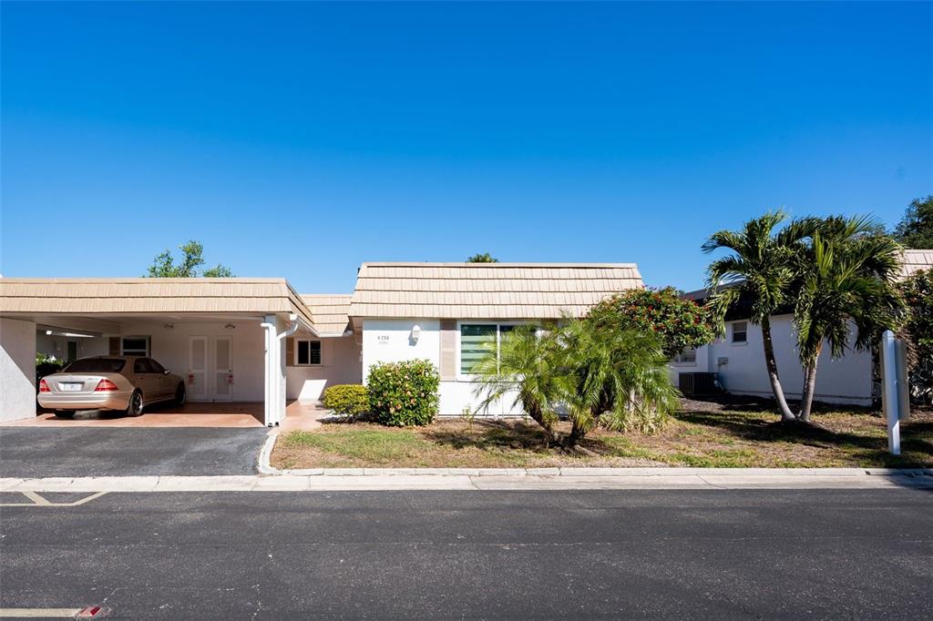 A single-story house with a carport, a tan tiled roof, and palm trees in front — 2305 RIVERBLUFF PARKWAY UNIT V256, SARASOTA, FL