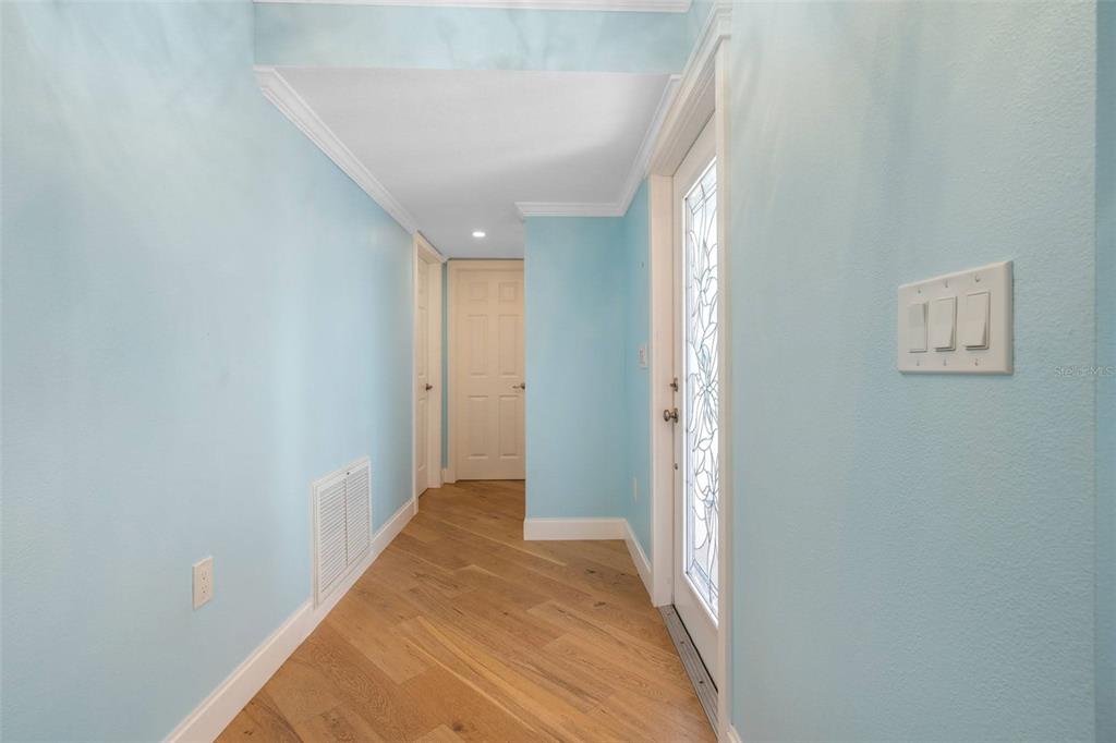 A hallway with light blue walls, wood flooring, and a glass-paneled entry door — 2305 RIVERBLUFF PARKWAY UNIT V256, SARASOTA, FL
