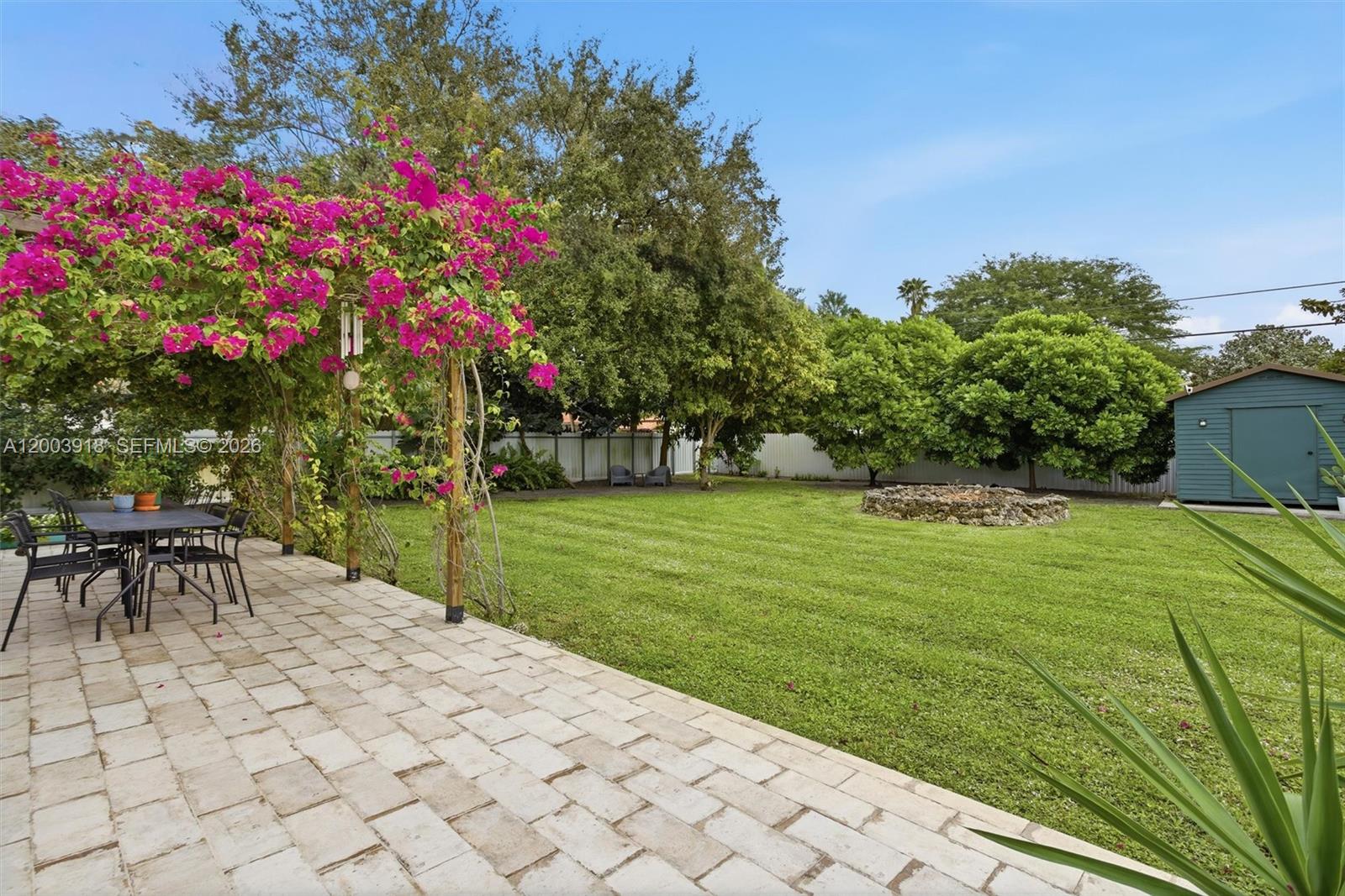 A backyard features a paved patio with a bougainvillea-covered pergola, a lawn, and a shed — 565 South Dr, Miami Springs FL 33166, MIAMI SPRINGS, FL