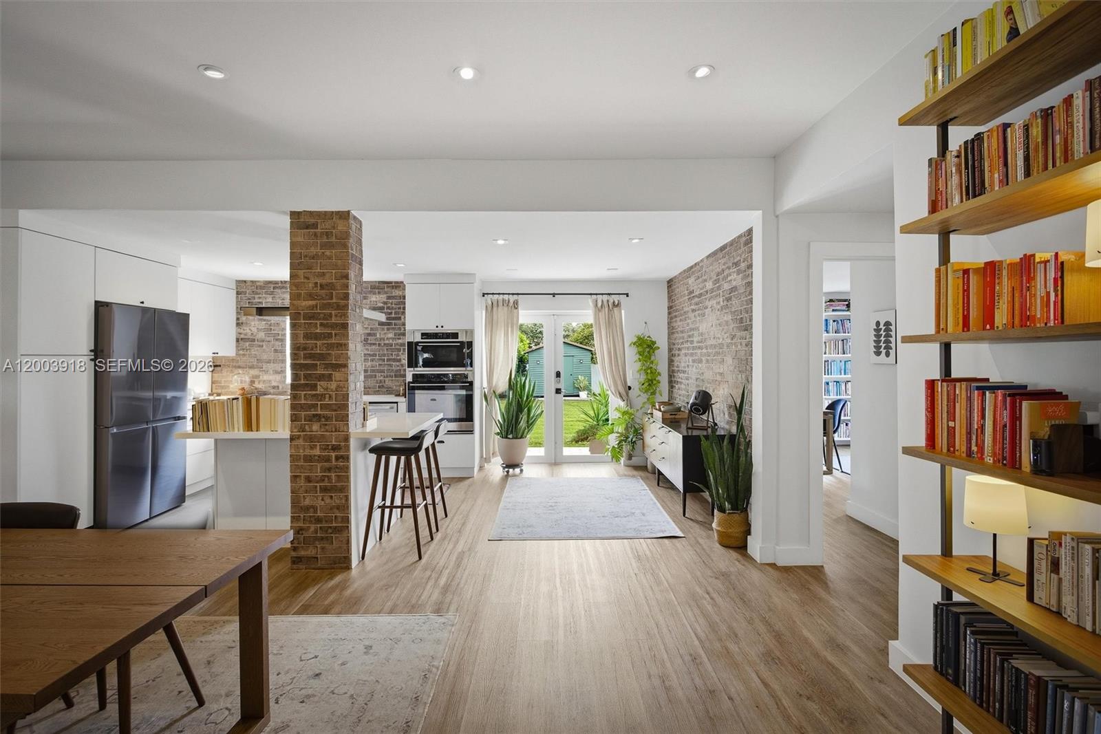 A kitchen and dining area featuring brick columns, light wood flooring, and a bookshelf — 565 South Dr, Miami Springs FL 33166, MIAMI SPRINGS, FL