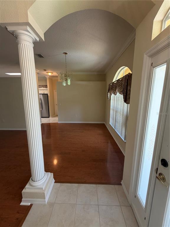 An entryway with tile flooring leads to a living area featuring hardwood floors and columns — 11855 TEE TIME CIRCLE, NEW PORT RICHEY, FL