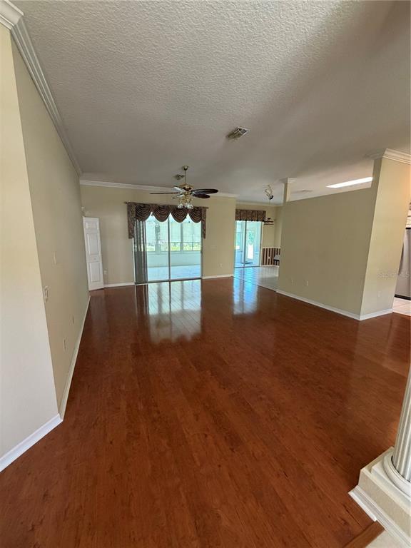 An open-concept living area features hardwood floors, a ceiling fan, and sliding glass doors — 11855 TEE TIME CIRCLE, NEW PORT RICHEY, FL