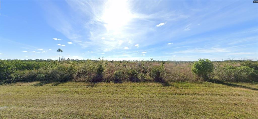 A wide, flat, undeveloped grassy lot under a bright blue sky with scattered clouds — 501 CALENDULA DRIVE, INDIAN LAKE ESTATES, FL