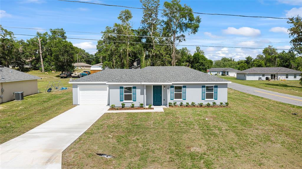 A single-story house with a gray exterior, blue shutters, a white garage, and a driveway — 29 JUNIPER PASS LANE, OCALA, FL