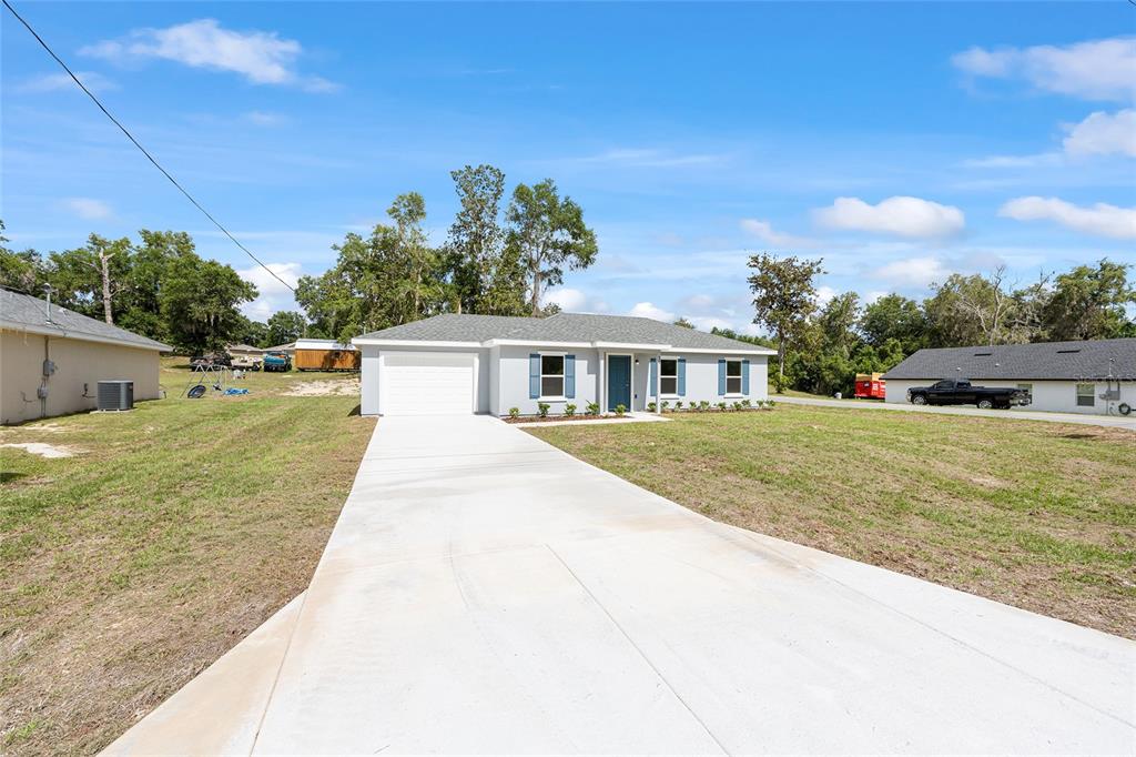 A single-story house with a gray exterior, blue shutters, and a concrete driveway — 29 JUNIPER PASS LANE, OCALA, FL