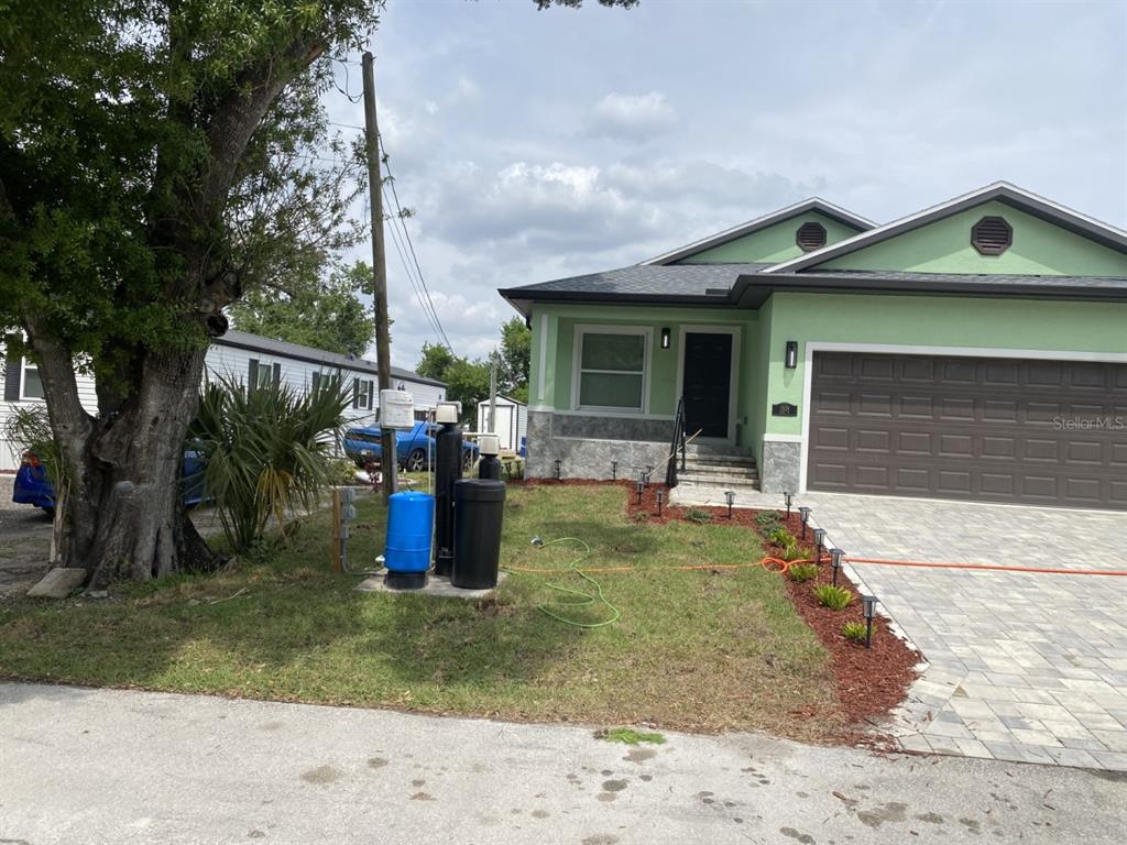 A light green house with a brown garage door and a front yard water system — 1938 SW DUKE STREET, ARCADIA, FL