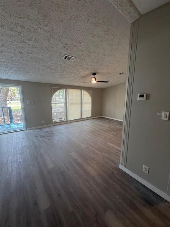 An empty living room features light wood-look flooring, a ceiling fan, and sliding glass doors — 17199 SE 97TH TERRACE, SUMMERFIELD, FL