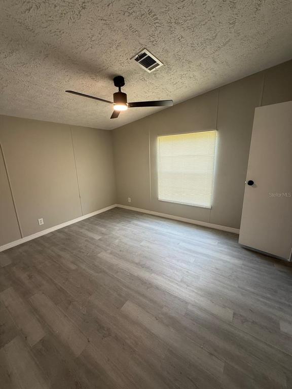 An empty bedroom features light gray walls, wood-look flooring, a ceiling fan, and a window — 17199 SE 97TH TERRACE, SUMMERFIELD, FL