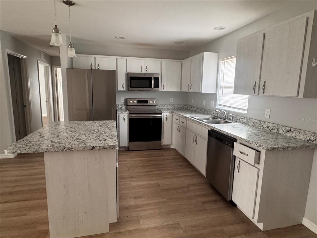 A kitchen features white cabinets, granite countertops, stainless steel appliances, and a central island — 625 N THIRTEENTH AVENUE, ARCADIA, FL