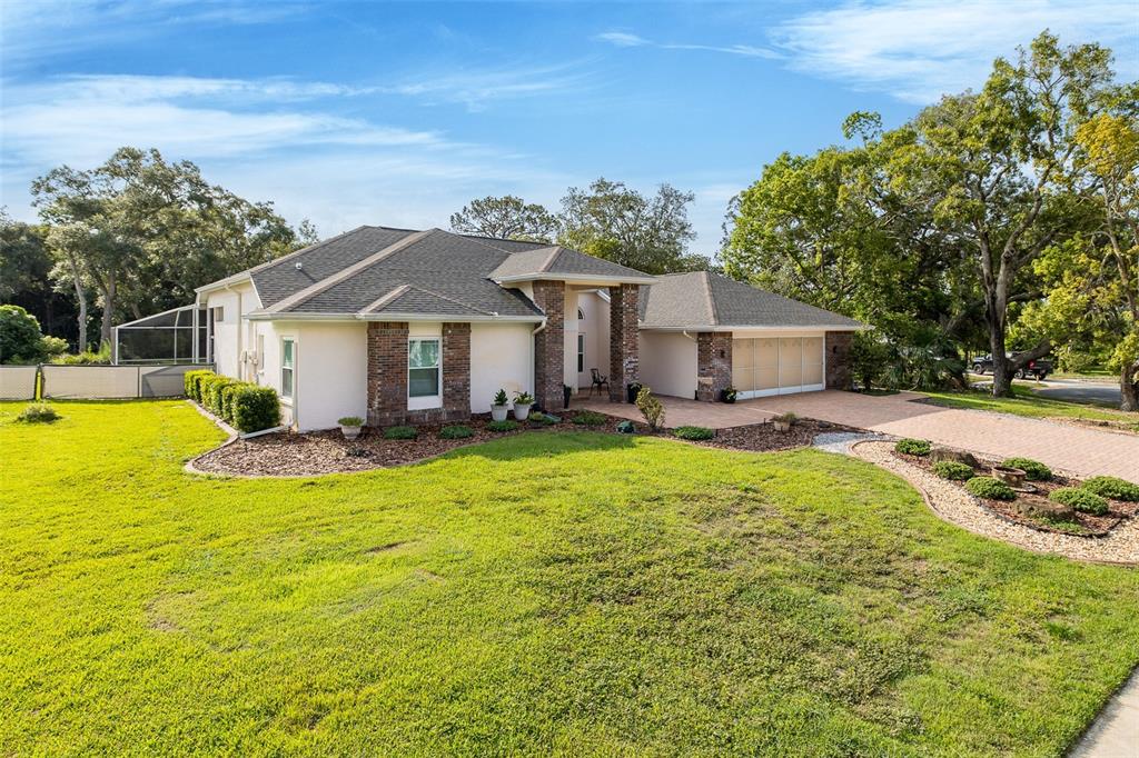 A single-story house with a brick facade, shingled roof, and a paved driveway — 18822 MAJESTIC OAK COURT, HUDSON, FL