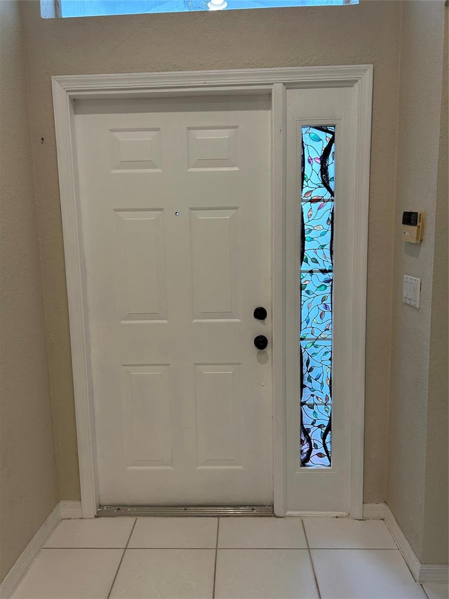 A white six-panel front door with a stained glass sidelight and black hardware — 3694 Miramontes Circle, Wellington FL 33414, WELLINGTON, FL