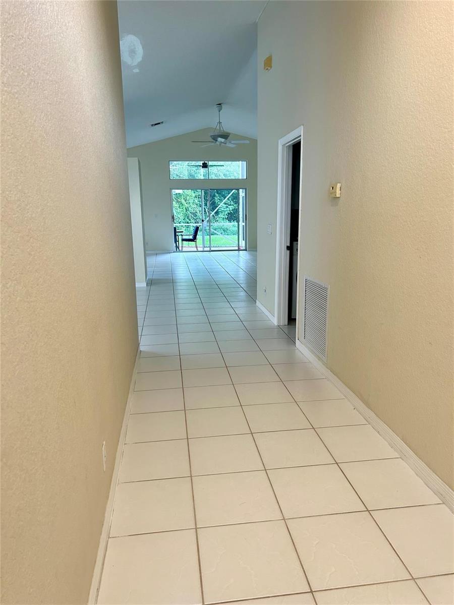 A tiled hallway leads to an open living area with sliding glass doors to a patio — 3694 Miramontes Circle, Wellington FL 33414, WELLINGTON, FL