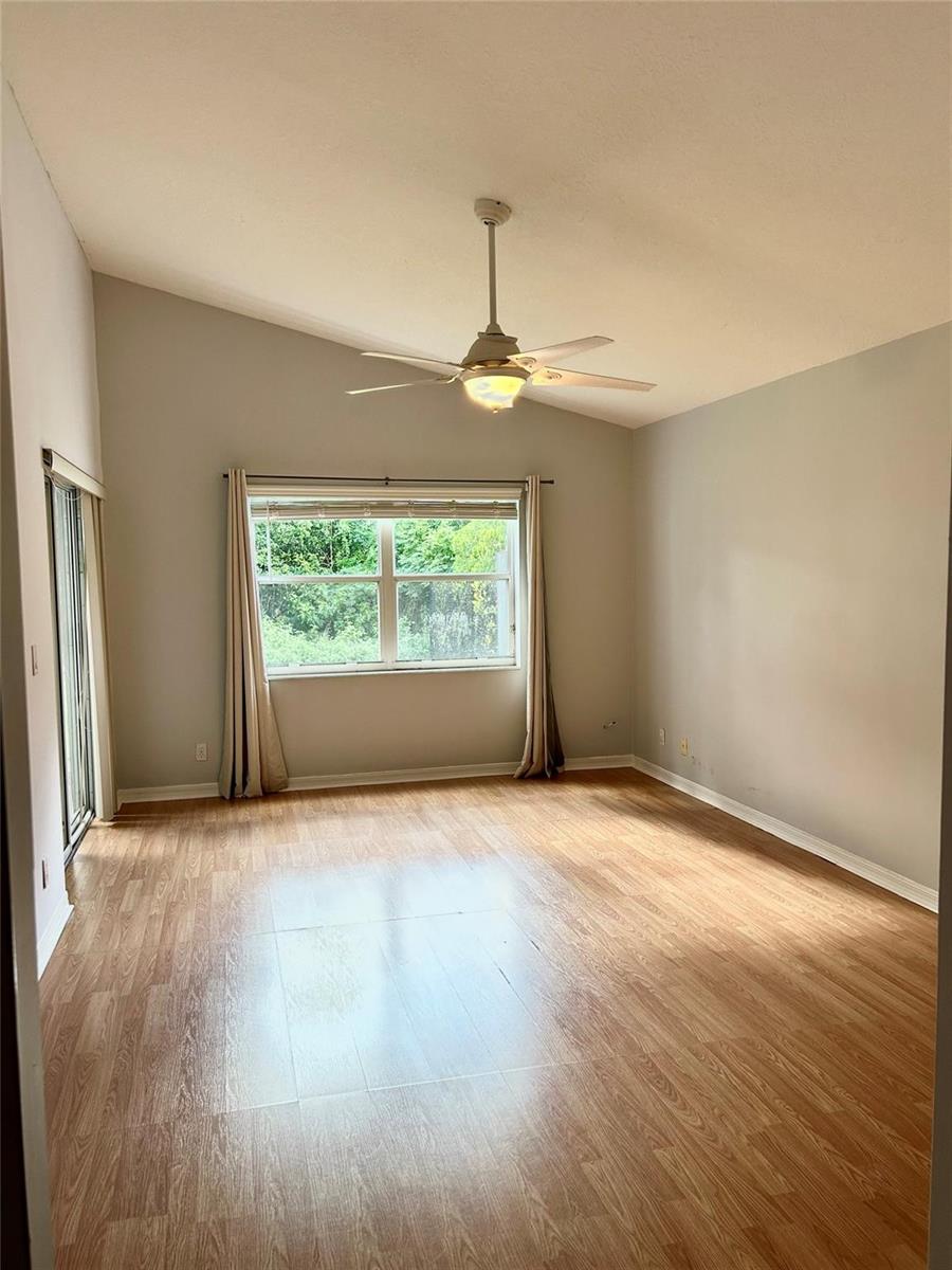 An empty room with light wood-look flooring, a vaulted ceiling, and a ceiling fan — 3694 Miramontes Circle, Wellington FL 33414, WELLINGTON, FL