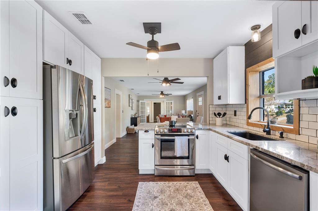 A kitchen with white cabinets, stainless steel appliances, and dark wood flooring — 504 PRADO PLACE, LAKELAND, FL