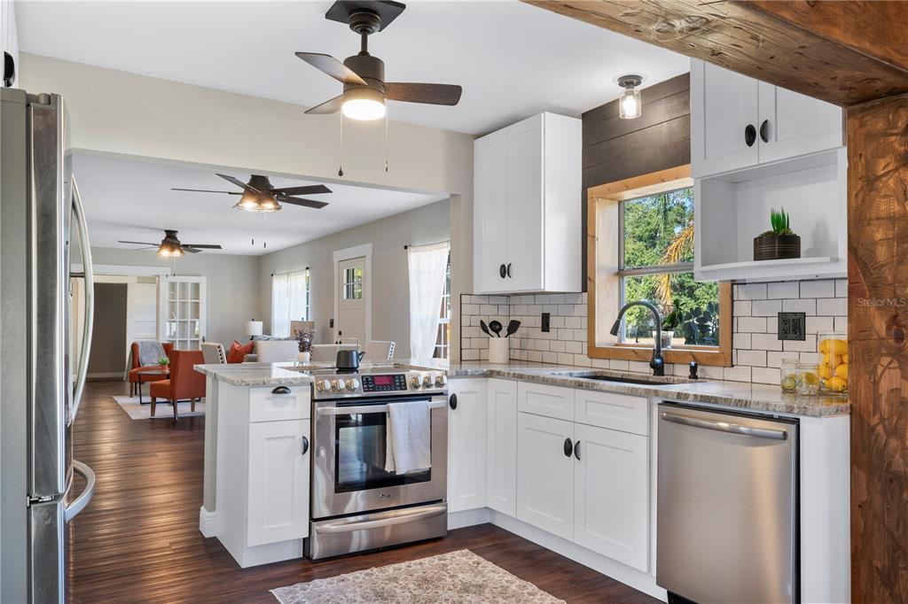 A kitchen with white cabinets, stainless steel appliances, and a window overlooking a green yard — 504 PRADO PLACE, LAKELAND, FL