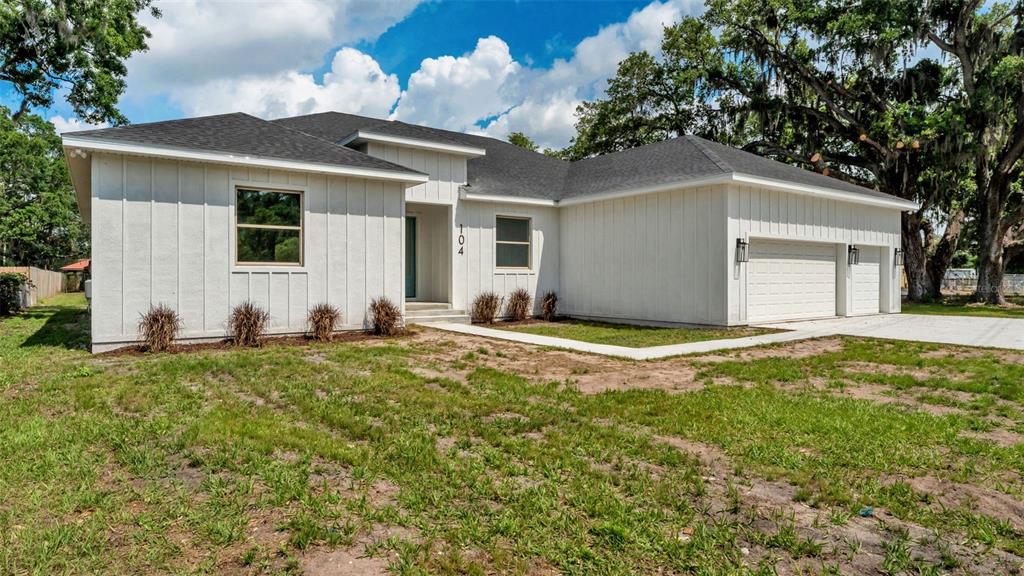 A white, single-story house with board-and-batten siding and a two-car garage — 104 THRASHER ROAD, PLANT CITY, FL