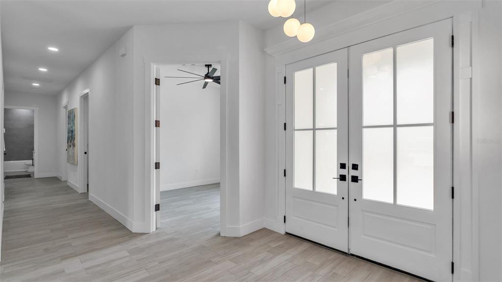 A bright entryway features white walls, light wood-look tile flooring, and double glass-paneled doors — 104 THRASHER ROAD, PLANT CITY, FL