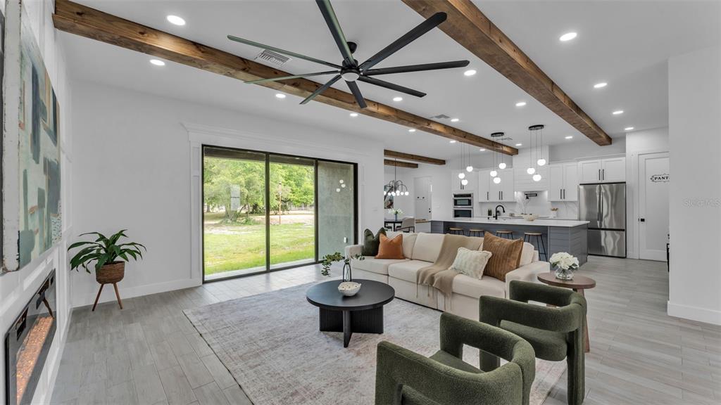 A modern living room features wood ceiling beams, a large ceiling fan, and a fireplace — 104 THRASHER ROAD, PLANT CITY, FL