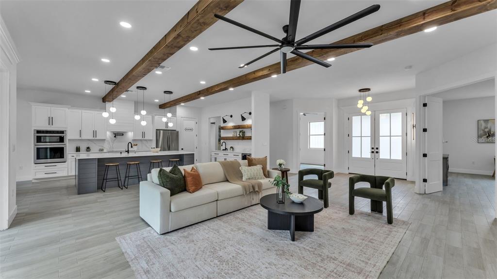 An open-concept living room and kitchen featuring wooden ceiling beams and a large ceiling fan — 104 THRASHER ROAD, PLANT CITY, FL
