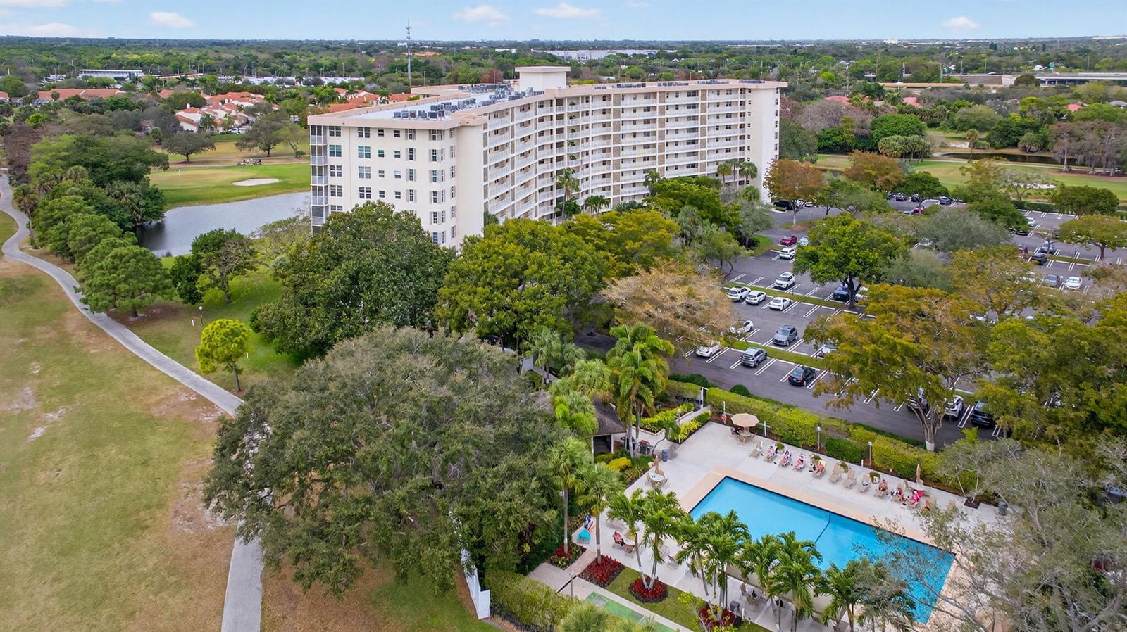 An aerial view shows a multi-story apartment building with a swimming pool and parking lot — 3507 Oaks Way # 501, Pompano Beach FL 33069, POMPANO BEACH, FL