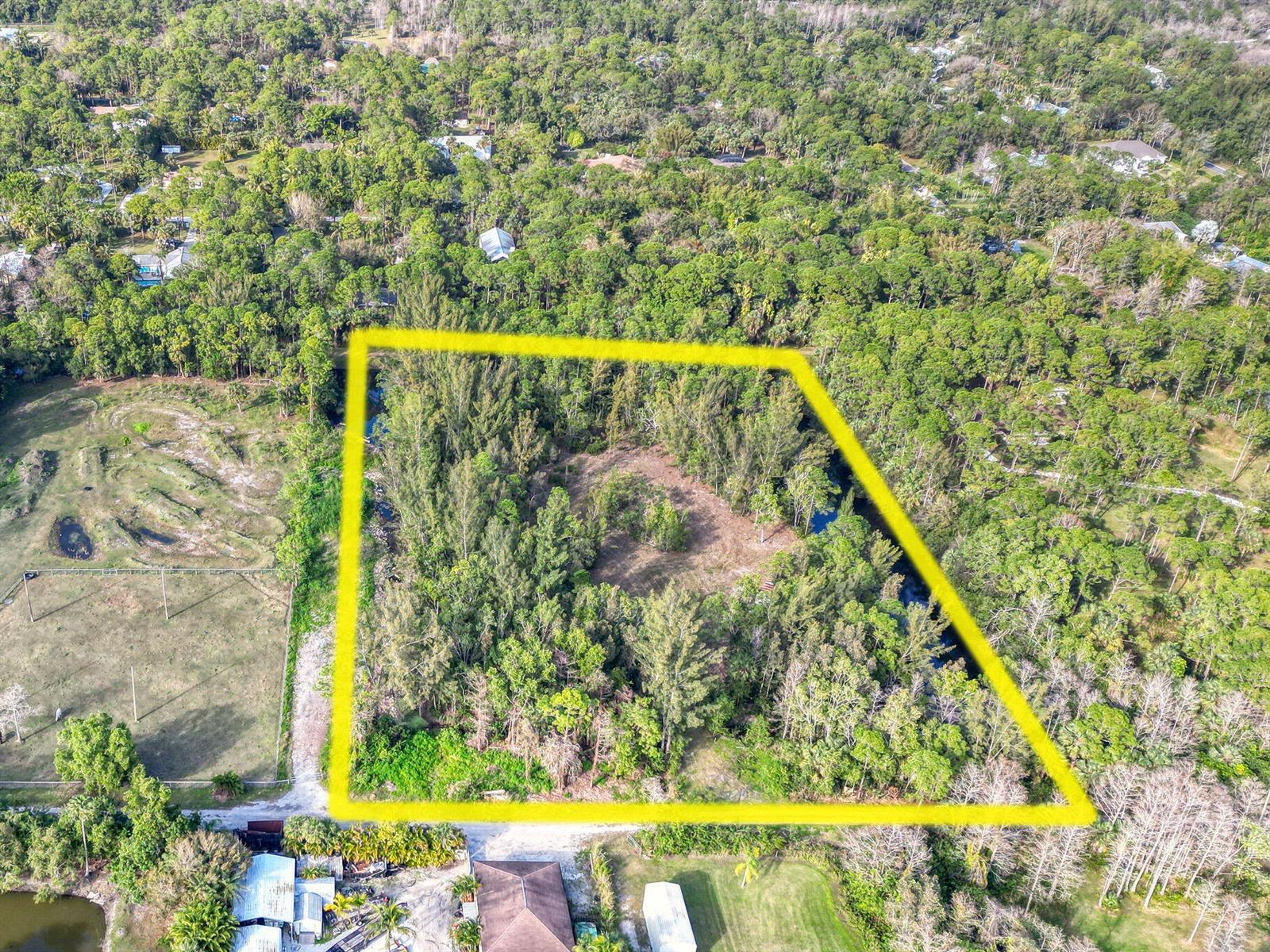 An aerial view shows a rectangular plot of land outlined in yellow amidst dense trees — 9205 Patricia Lane, Jupiter FL 33478, JUPITER, FL