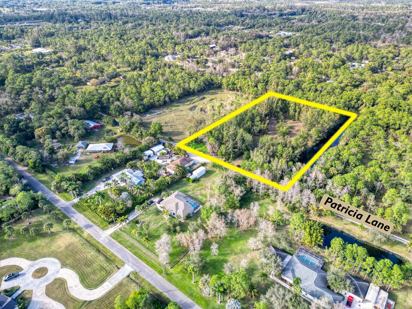 An aerial view shows a rectangular plot of land outlined in yellow near a road — 9205 Patricia Lane, Jupiter FL 33478, JUPITER, FL