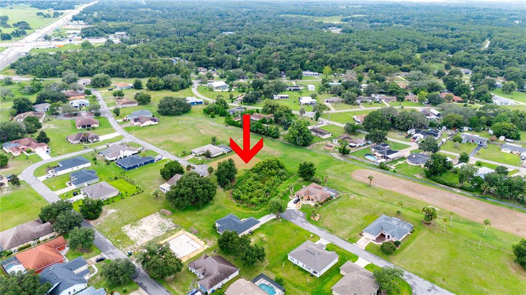 An aerial view shows a vacant, tree-covered residential lot marked by a large red arrow — 5413 BOXTREE CT, DADE CITY, FL