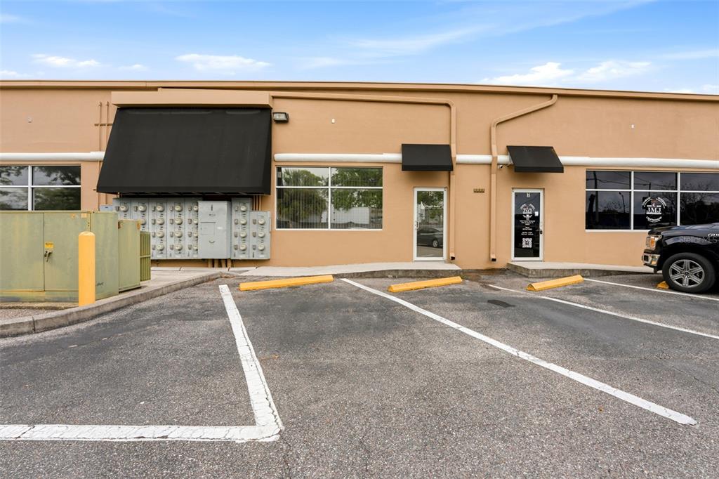 The exterior of a commercial building features a tan facade, two glass entry doors, and parking — 5404 HOOVER BOULEVARD UNIT 8, TAMPA, FL