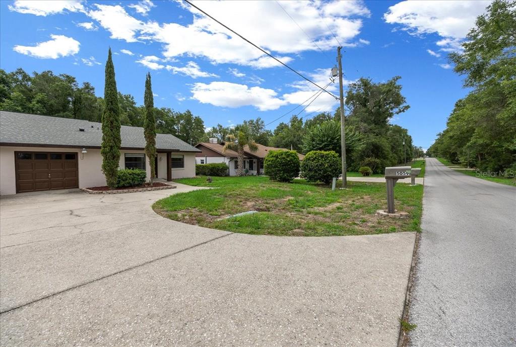 A single-story house with a concrete driveway and a mailbox stands beside a paved road — 5059 SW 196TH AVENUE, DUNNELLON, FL