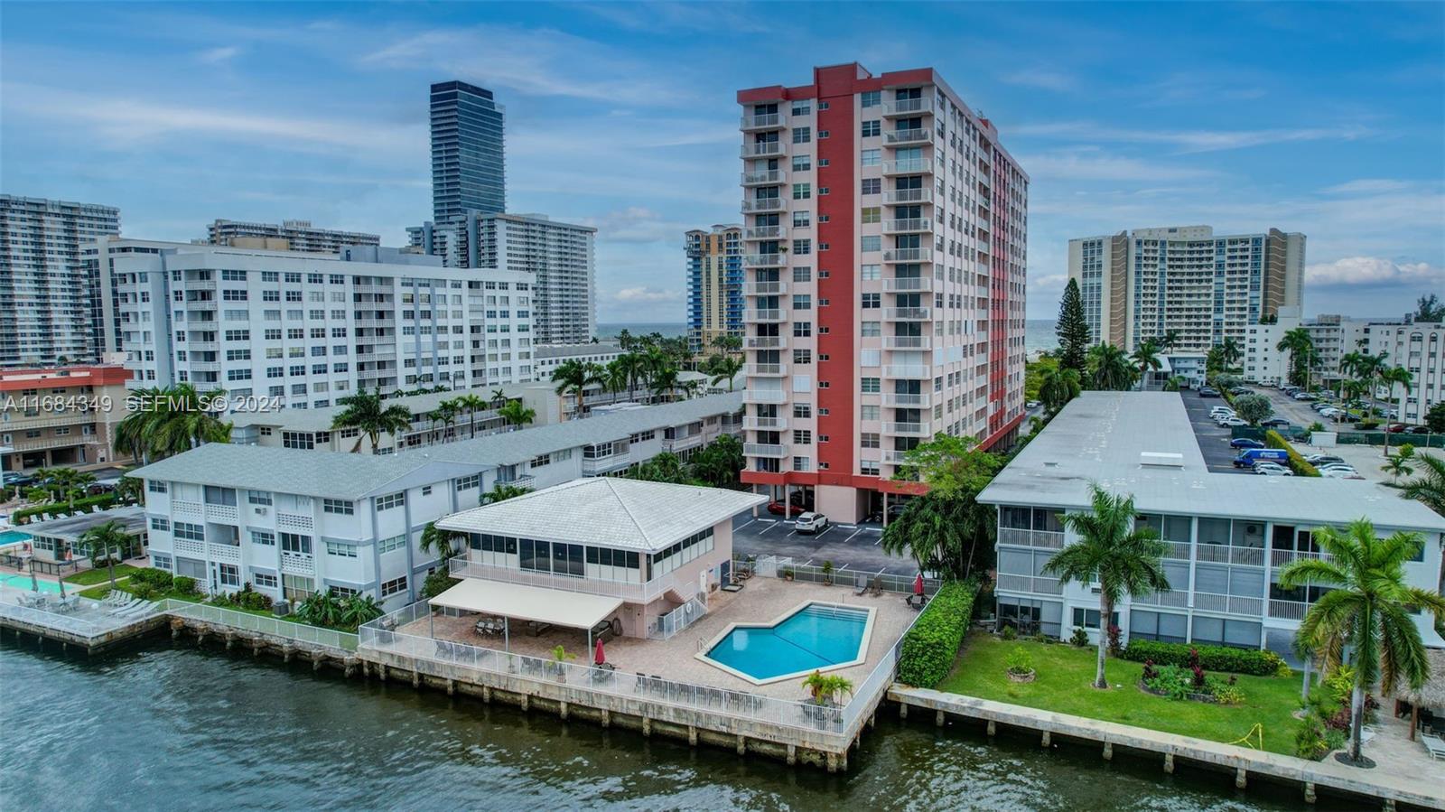 An aerial view shows a waterfront apartment complex with a pool and surrounding buildings — 3161 S Ocean Dr # 203, Hallandale Beach FL 33009, HALLANDALE BEACH, FL