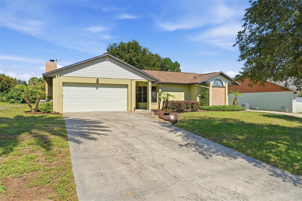 A single-story house with a light green exterior, a two-car garage, and a concrete driveway — 103 RIDGECREST DRIVE, EUSTIS, FL