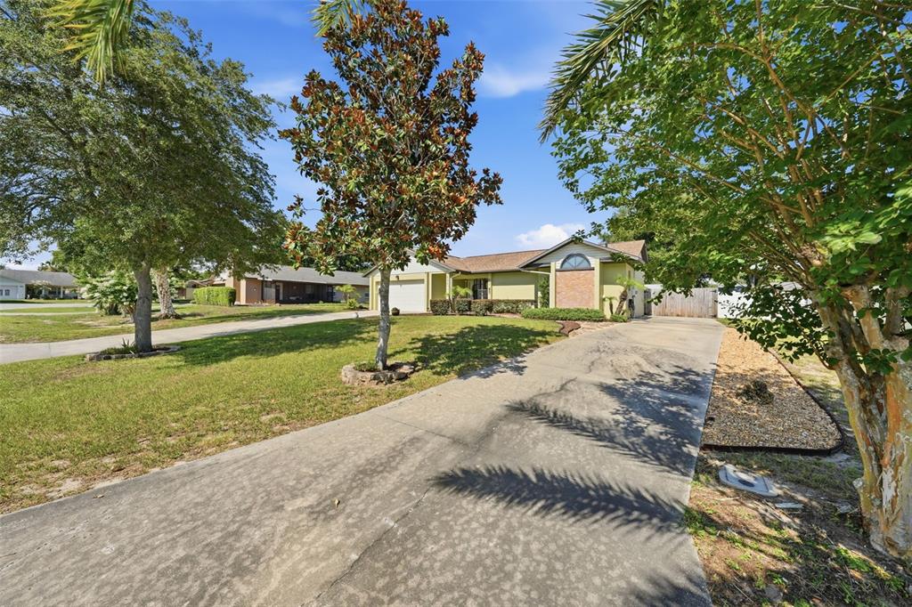 A single-story house with a concrete driveway, a front lawn, and several mature trees — 103 RIDGECREST DRIVE, EUSTIS, FL